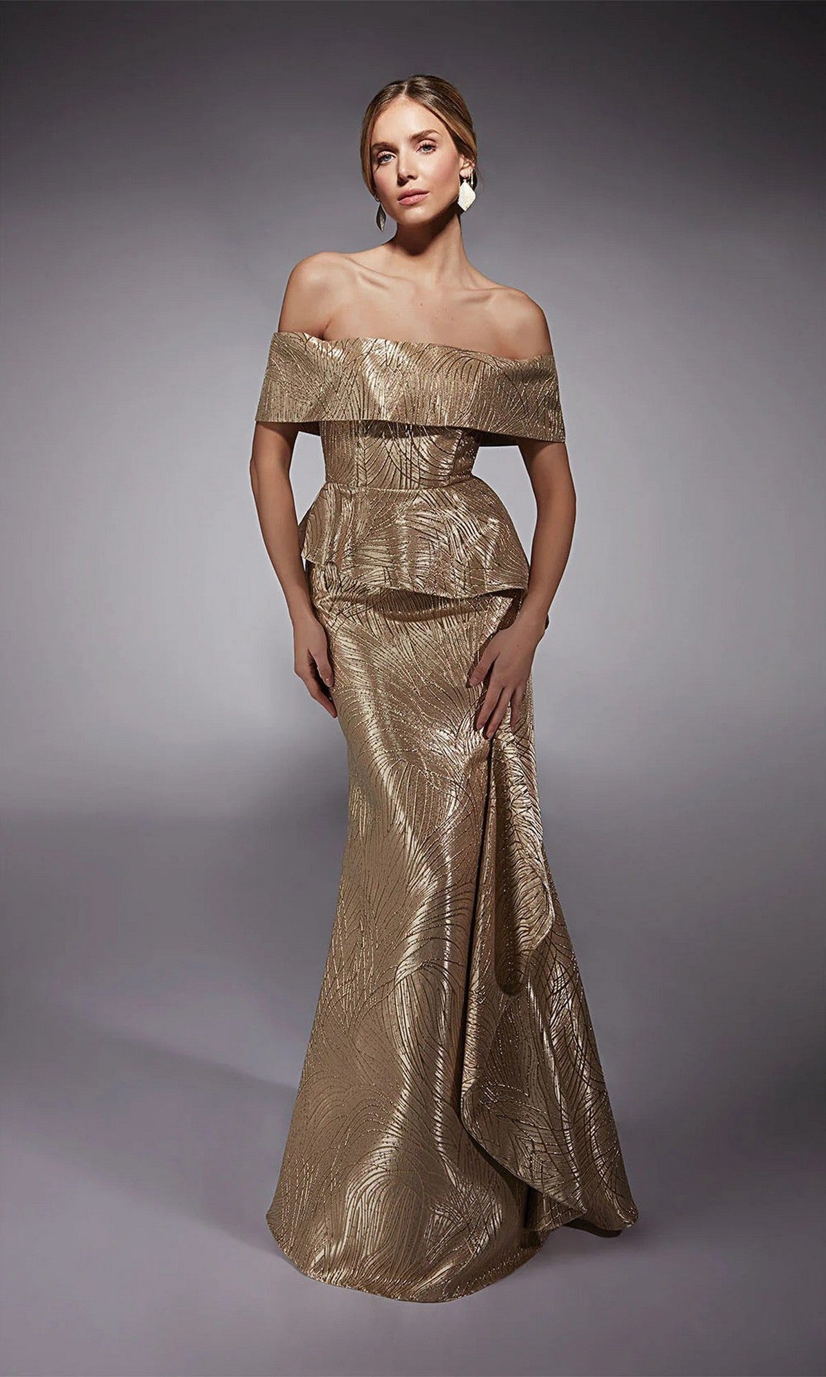 A woman poses against a neutral background in the Alyce 27759 long formal dress, featuring metallic gold color, an off-the-shoulder fitted silhouette, peplum detail, and a subtle textured pattern.